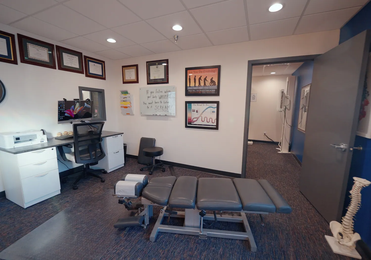 Adjustment room with a chiropractic table and spine model