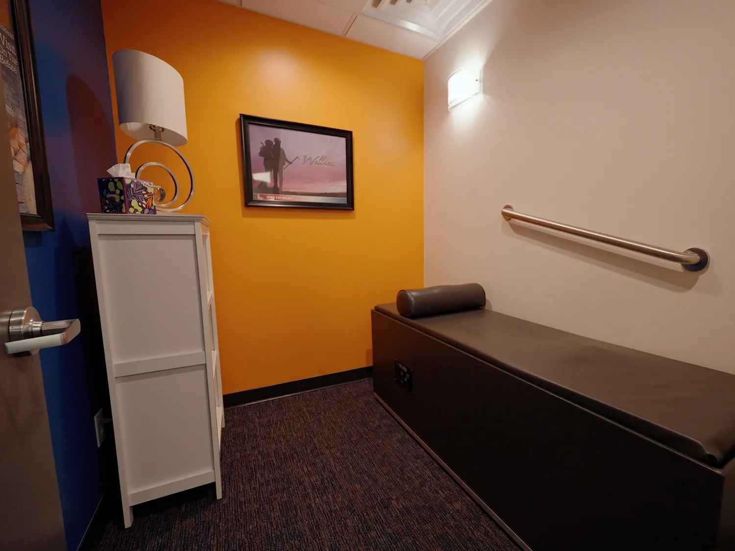 Private treatment room with an orange accent wall and treatment table