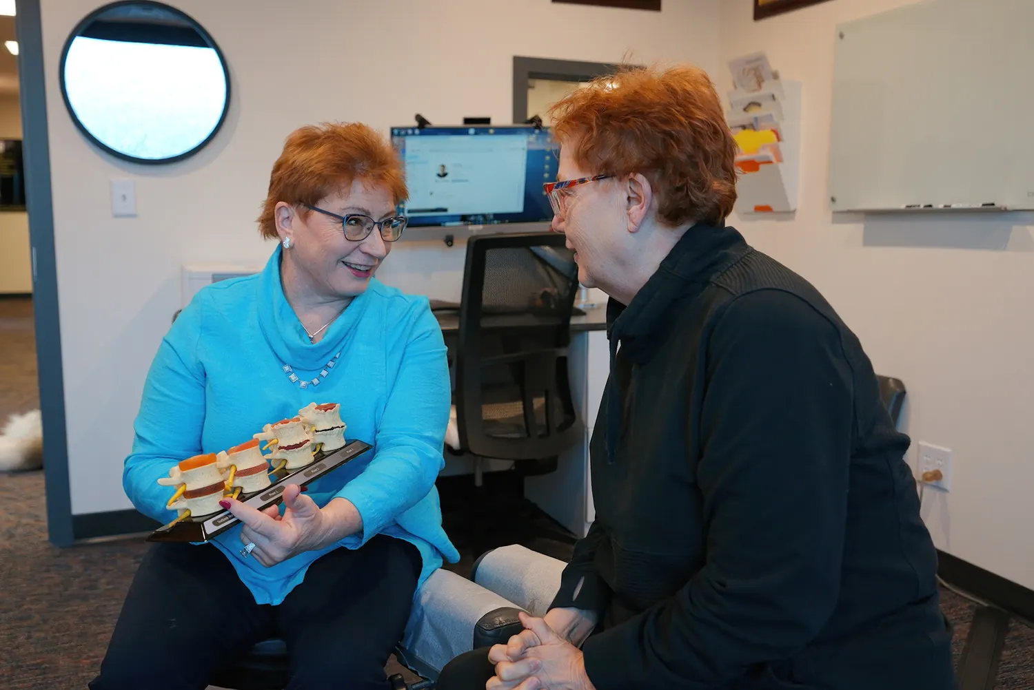 Dr. Trish Wolff using a vertebrae model during a patient consultation